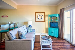 Una sala de estar con un sofá, sillas, un televisor y una silla de mimbre con una bandeja.