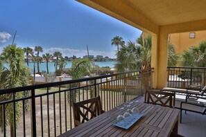 Ein Balkon mit Esstisch, mit Blick auf einen Pool und Palmen.