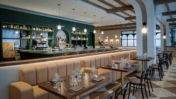A restaurant with a long counter, multiple seating areas, and a bar.