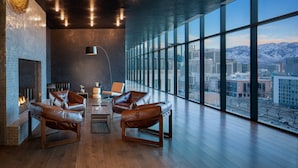 Un intérieur moderne avec des fauteuils en cuir, une cheminée et une grande fenêtre donnant sur la ville.