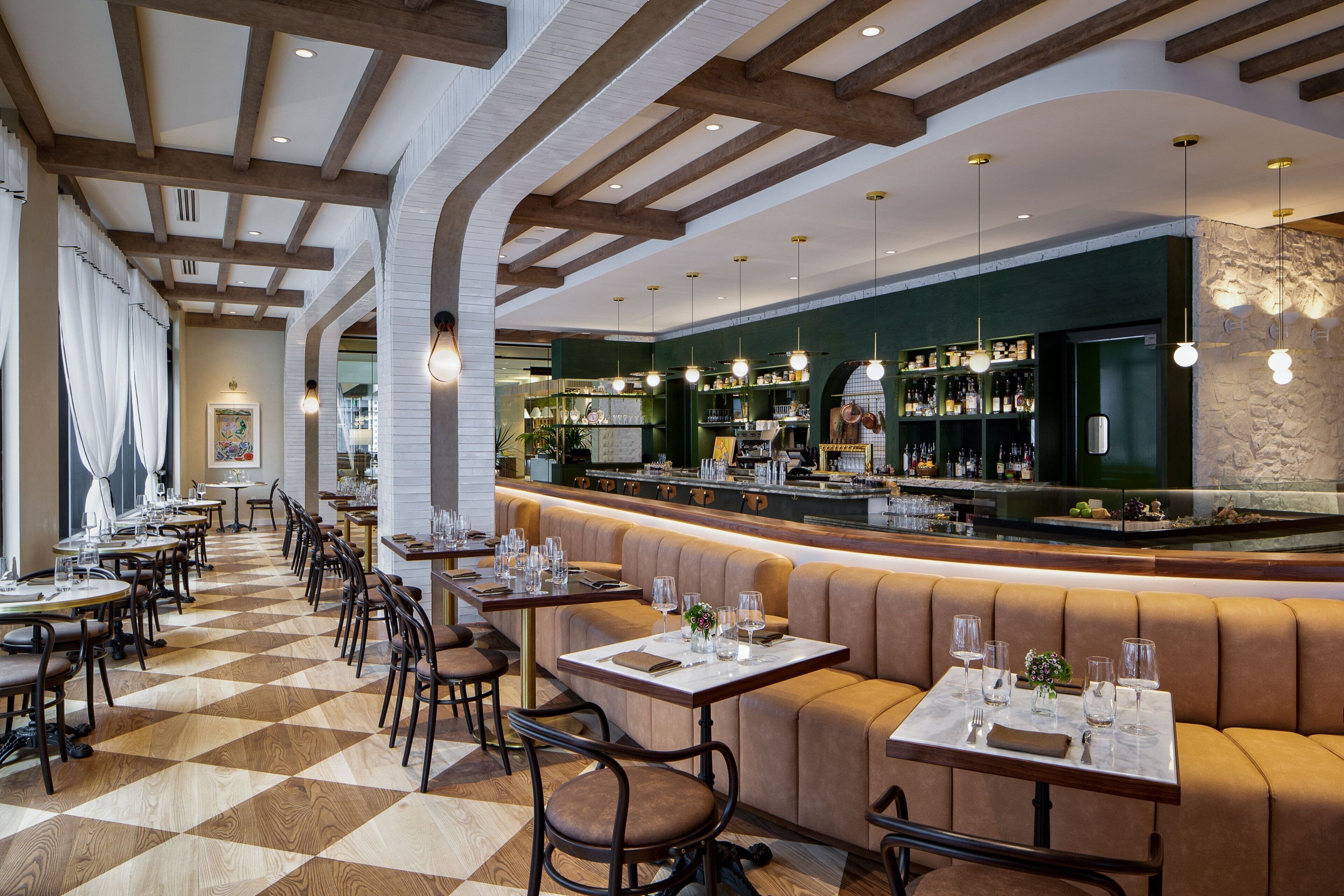 Un ristorante con pavimento a scacchi, travi in legno e un'area bar con scaffali pieni di bottiglie.