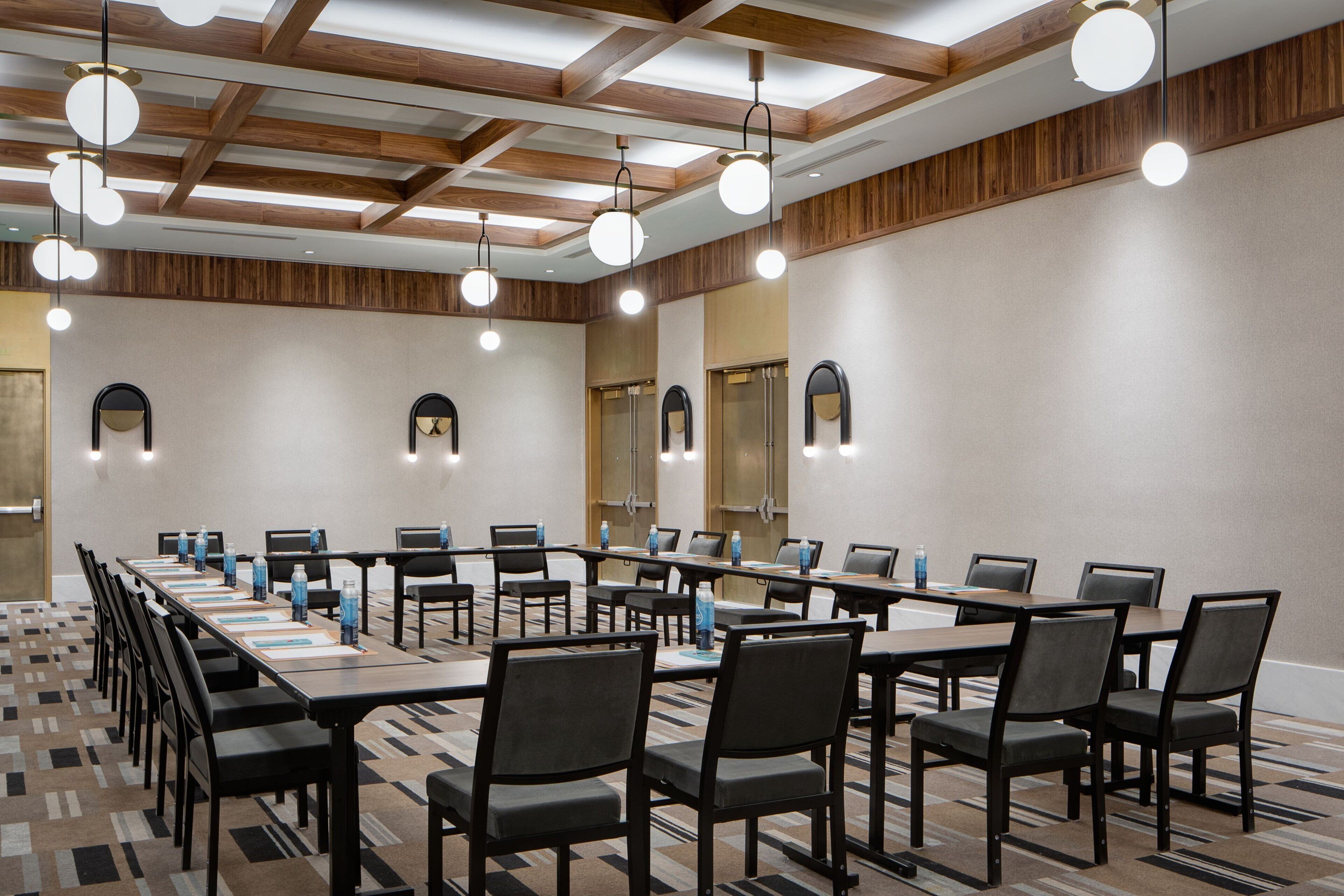 A conference room with long tables, chairs, and overhead lighting.