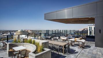 Une terrasse sur le toit avec des sièges extérieurs, une vue sur la ville et une architecture moderne.
