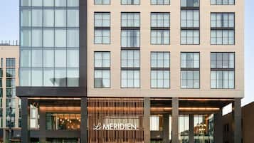 A modern hotel with a prominent 'Le Meridien' sign, large windows, and a flat facade.