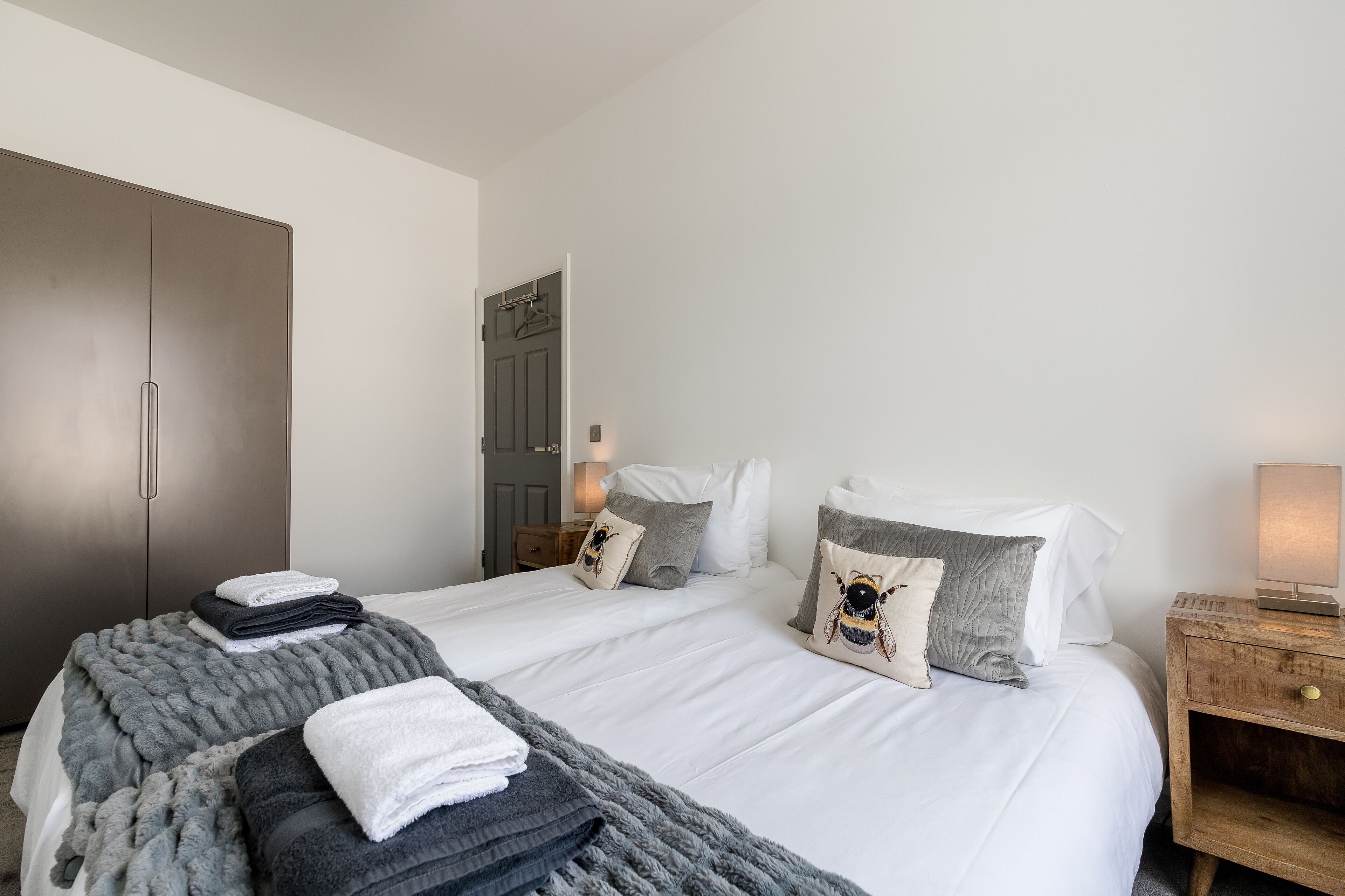 A neatly arranged bedroom with a bed, bedside tables, and a wardrobe.