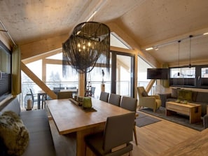 Ein geräumiges Loft mit hohen Decken, großen Fenstern, einem Holzespeisesaal und einer gemütlichen Sitzecke.