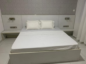 Restful retreat with a large bed and two nightstands, each with a lamp and power outlet.
