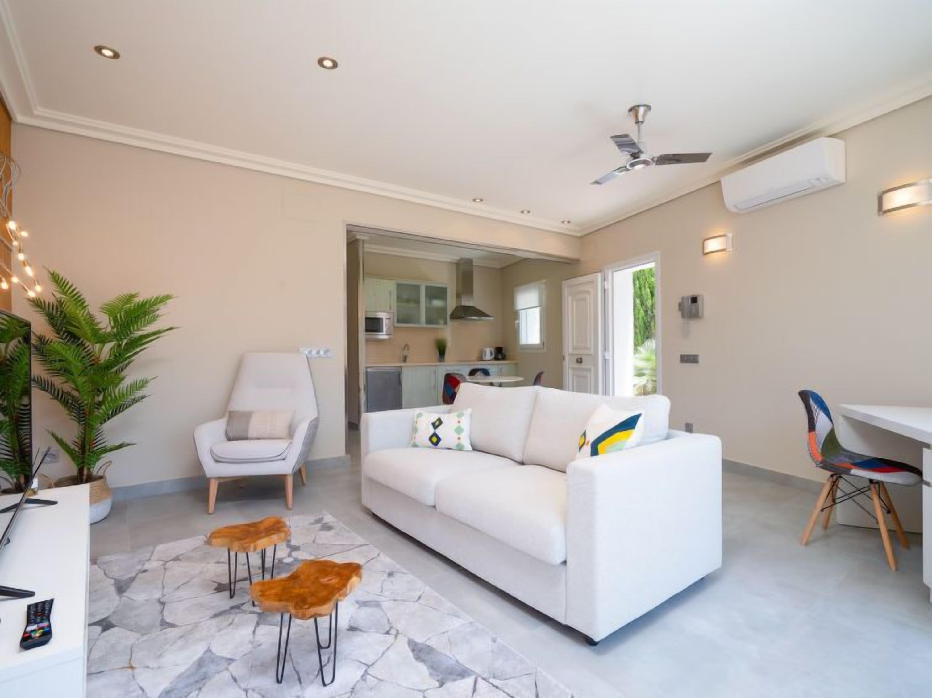 Un salon moderne avec un canapé blanc, un fauteuil, une table basse et un coin repas comprenant une chaise et une table.
