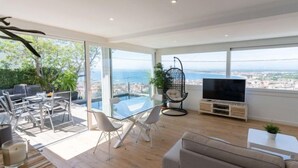 Una sala de estar moderna con una mesa de comedor de vidrio, un sofá y un televisor.