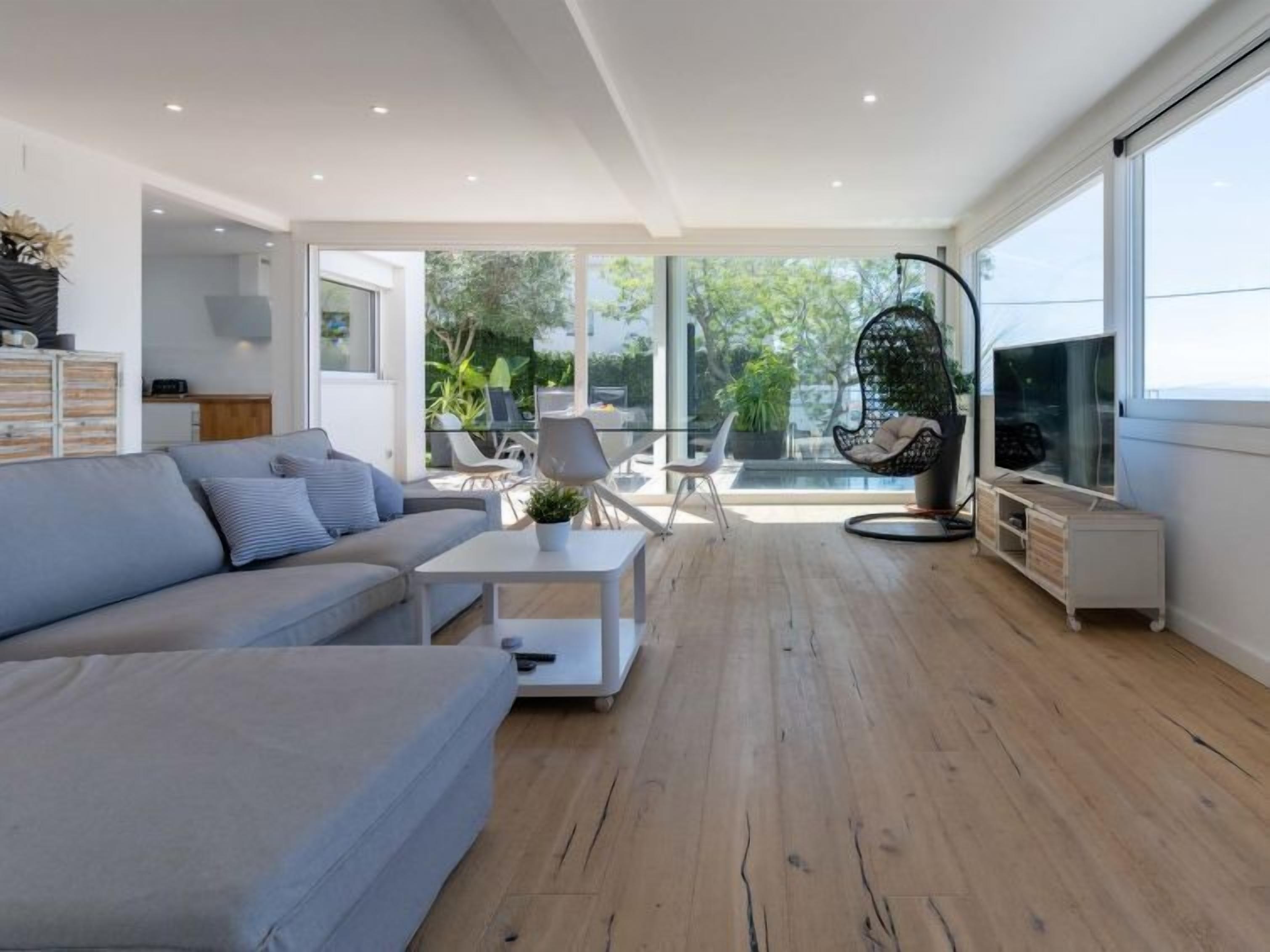 Ein modernes Wohnzimmer mit einem grauen Sofa, einem Couchtisch und einer TV-Konsole.