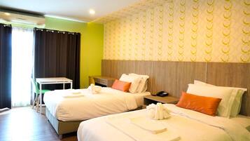 A hotel room with two beds, a desk, and a chair.