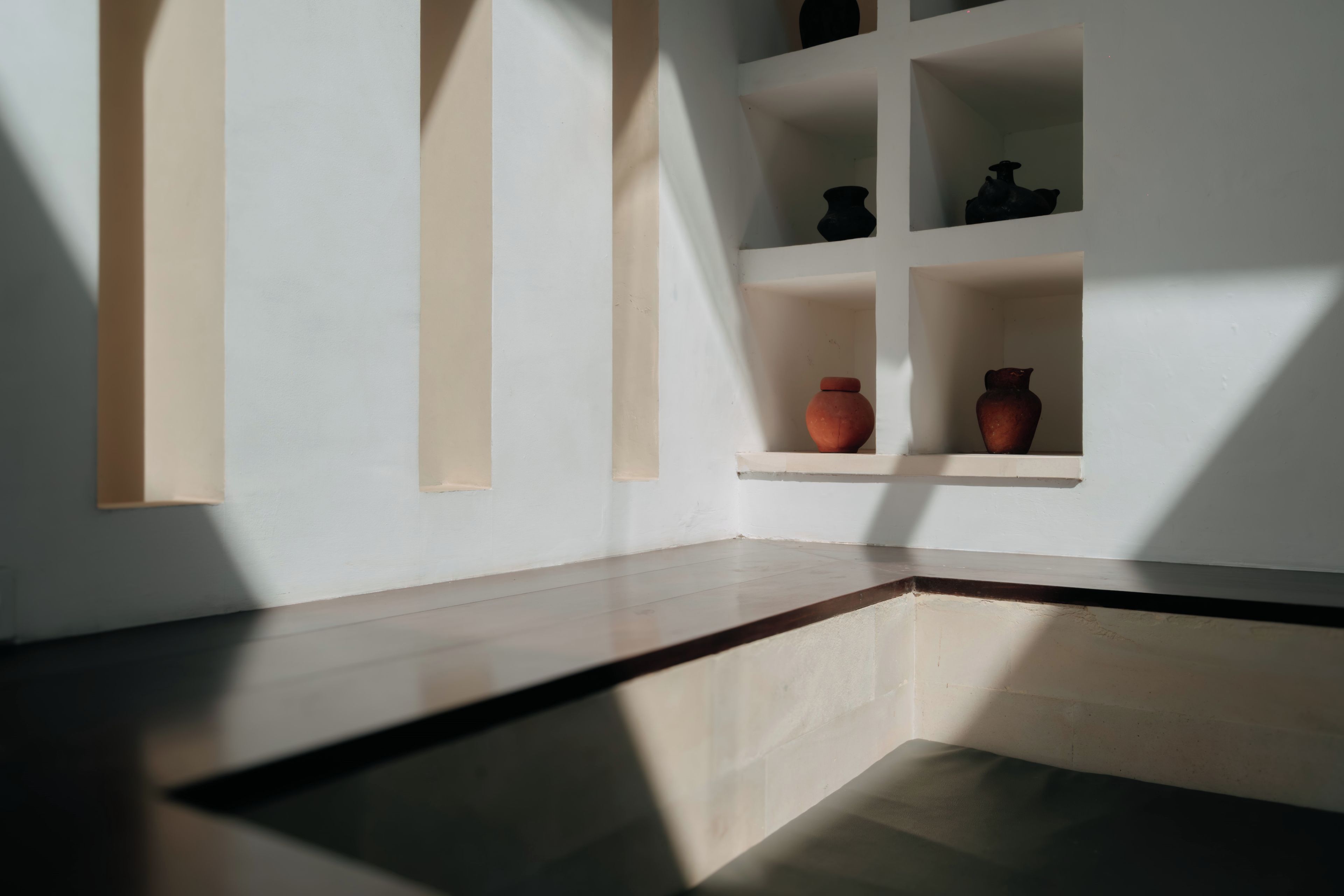 A room with a sloped ceiling, recessed shelving, and a polished floor.