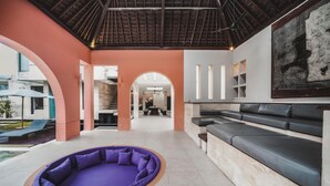 Un intérieur moderne avec un espace salon aux couleurs violettes, un escalier et un grand tableau accroché au mur.