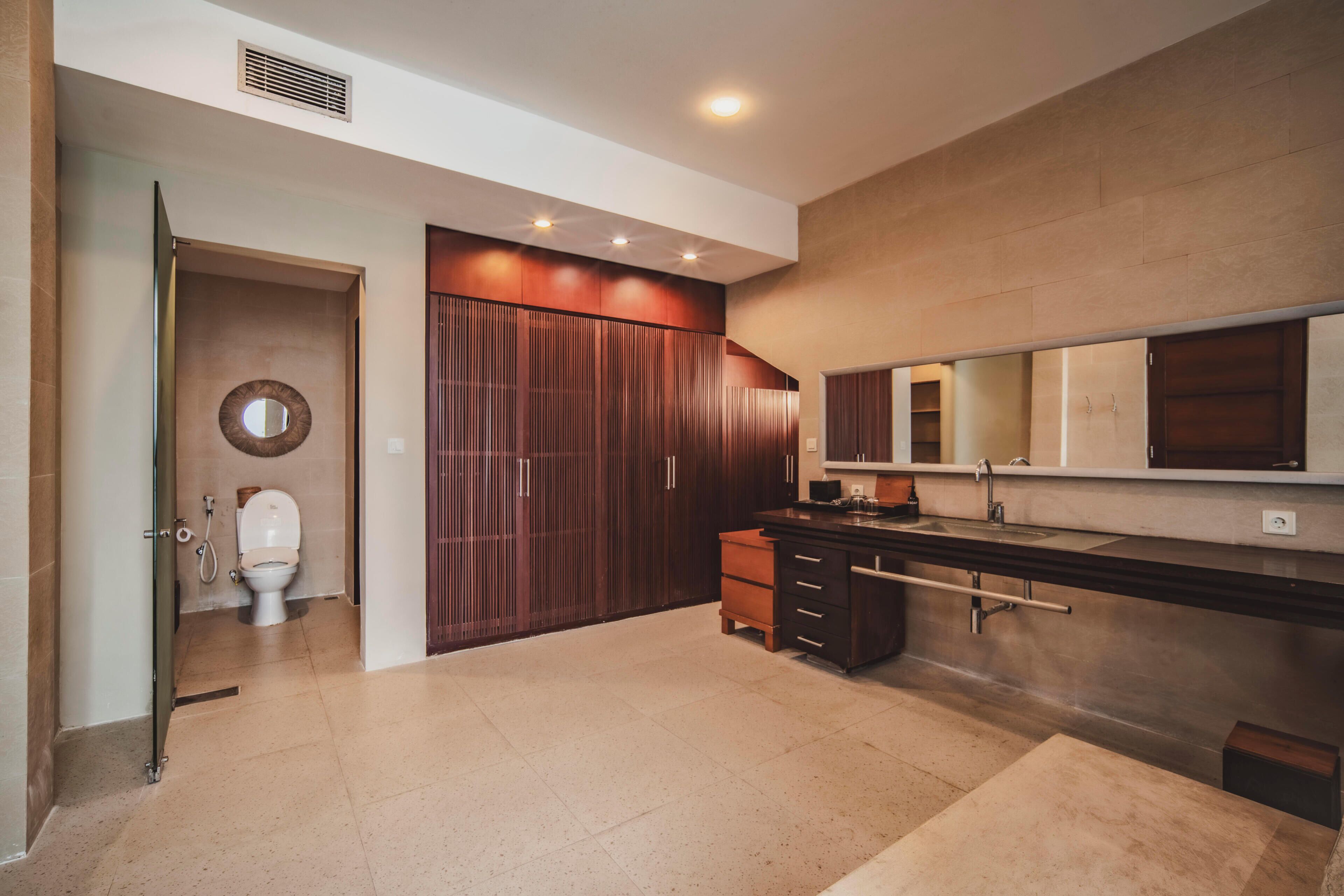 Un baño moderno con inodoro, ducha y un espejo grande.