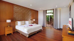 Une chambre spacieuse avec un grand lit, des boiseries, une télévision et un balcon agrémenté de rideaux.