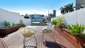 Eine Dachterrasse mit Pool, zwei weißen Stühlen und unterschiedlichen Pflanzen.