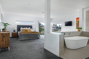Une chambre moderne avec un grand lit, une table de chevet, une commode et une vue sur la ville.