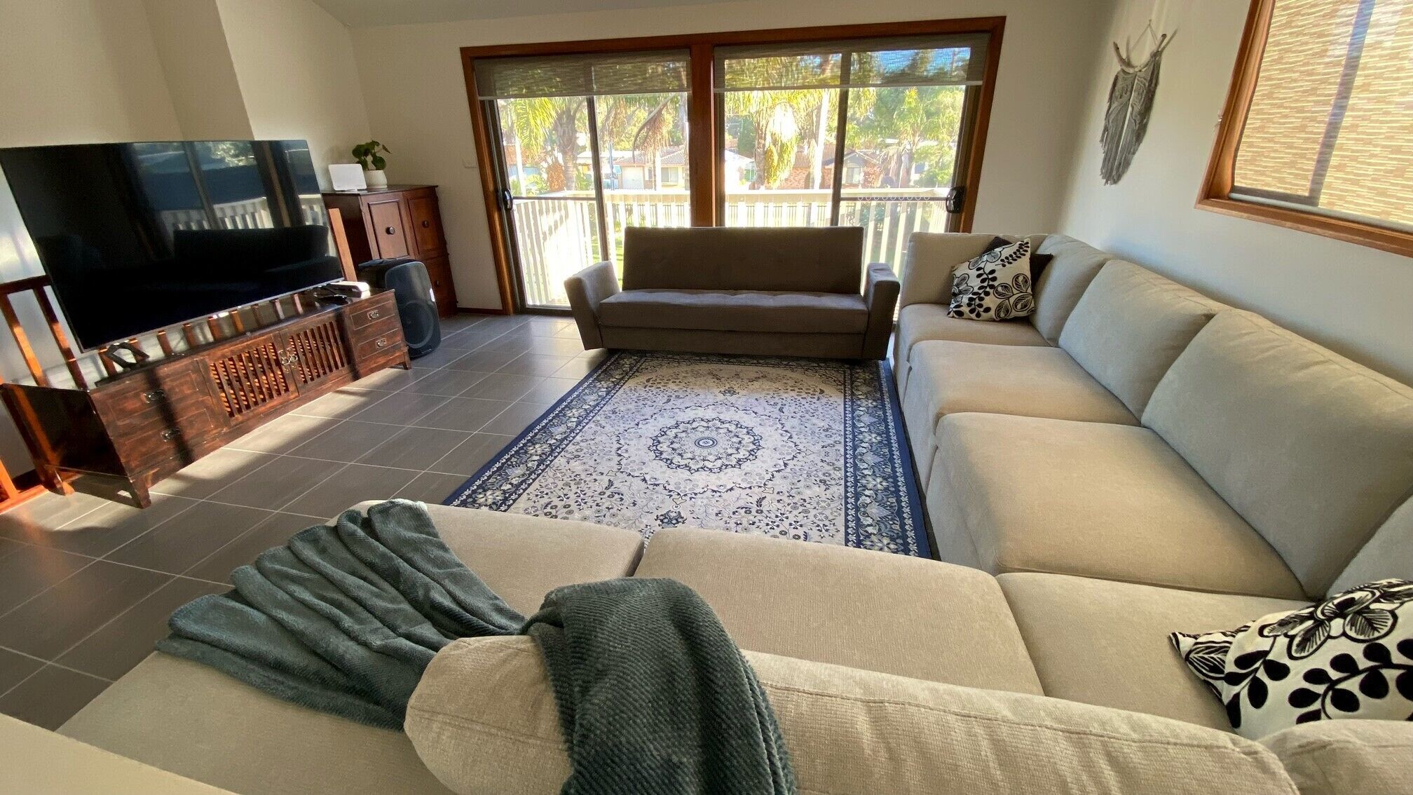A living room with a sofa, a television, a coffee table, and a patterned rug.