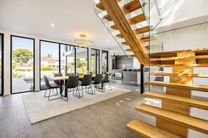 A modern interior with a dining area, kitchen, and a staircase.