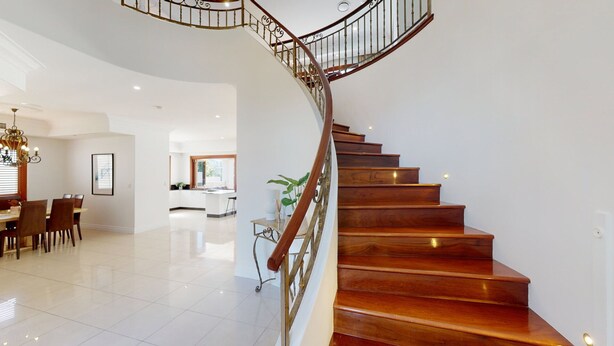 A spacious interior with a wooden staircase, a dining area, and a kitchen.