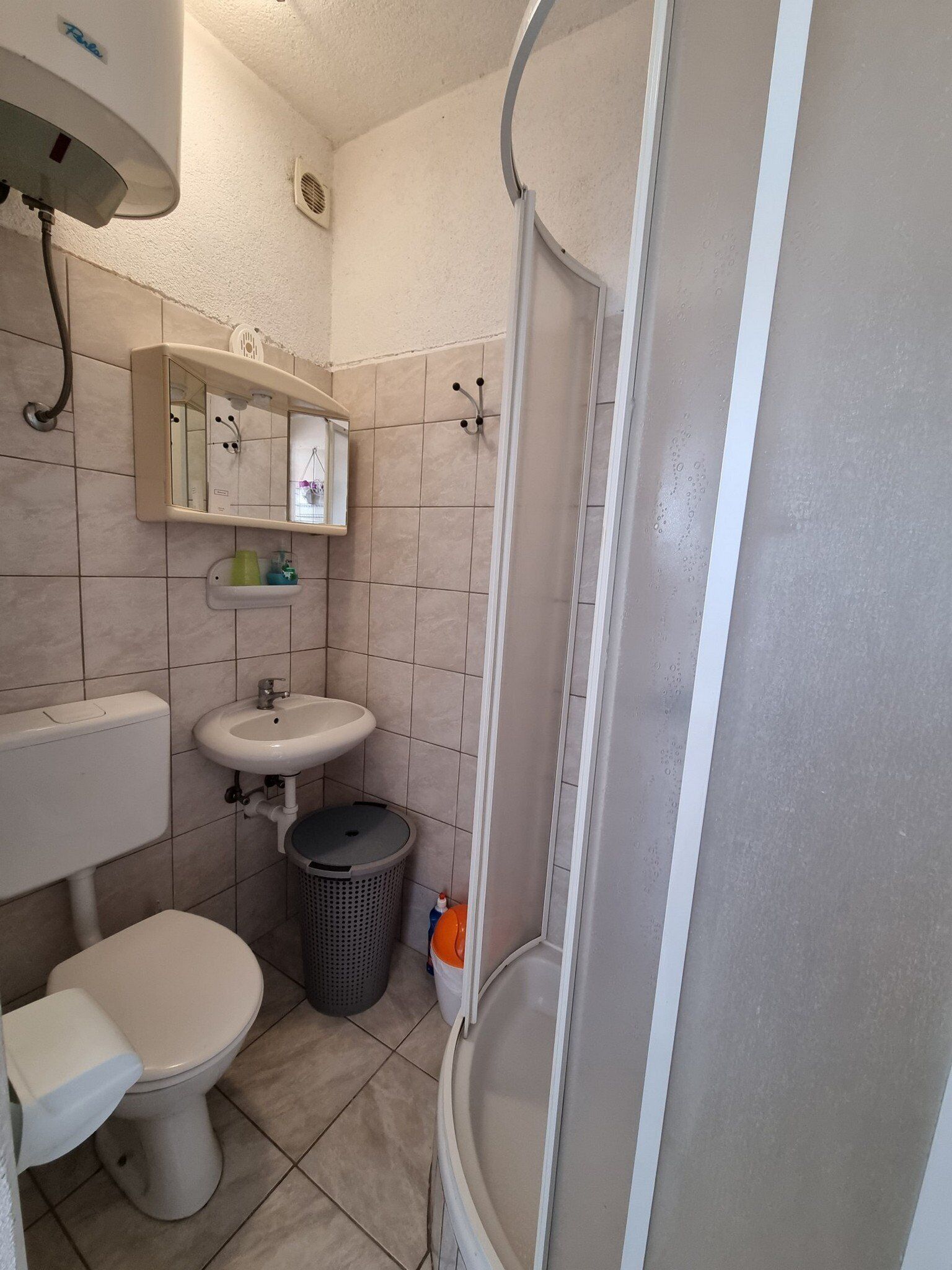 A bathroom with a toilet, sink, mirror, and shower.
