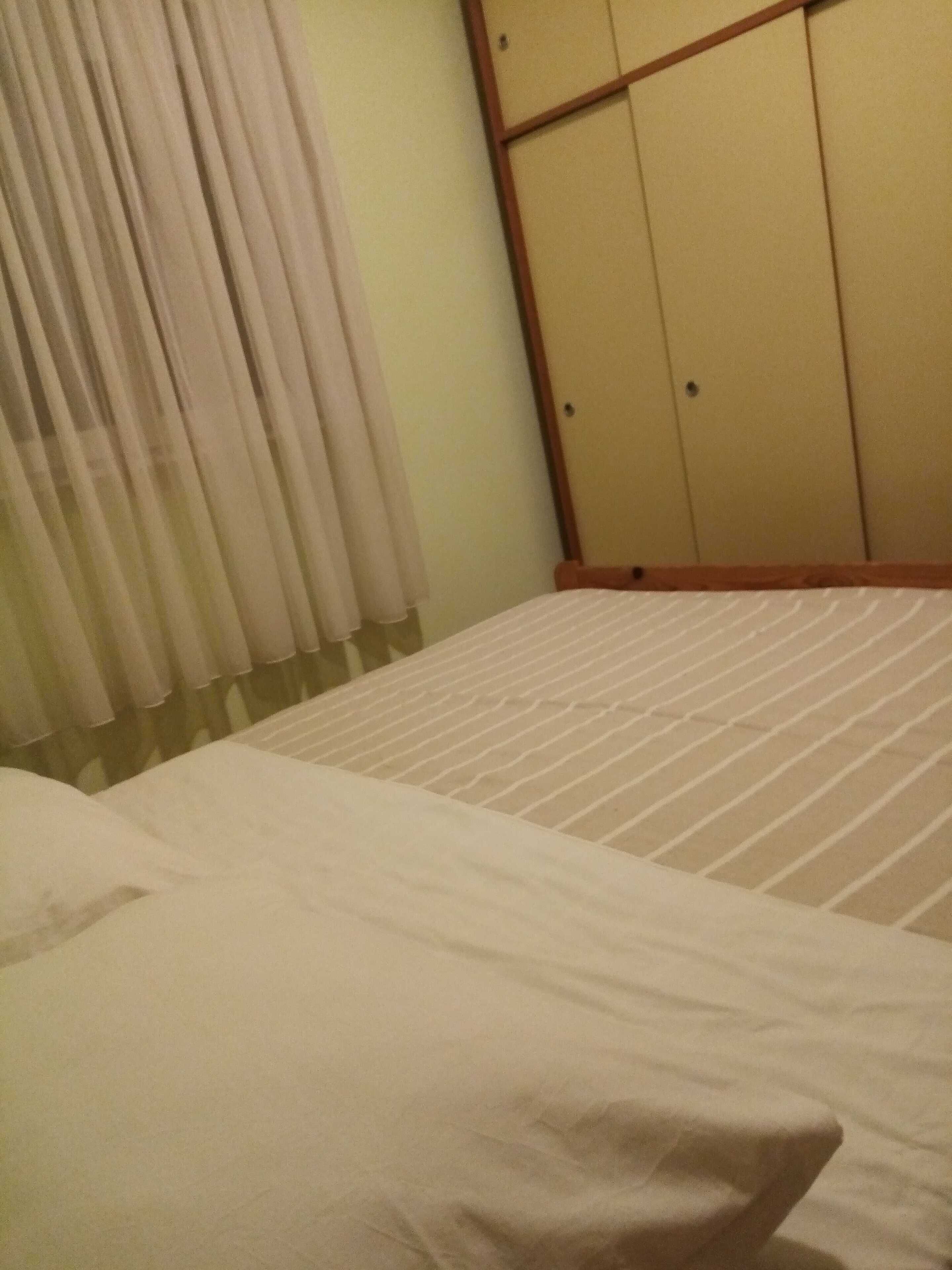 Une chambre avec un lit, une armoire et une fenêtre avec des rideaux.