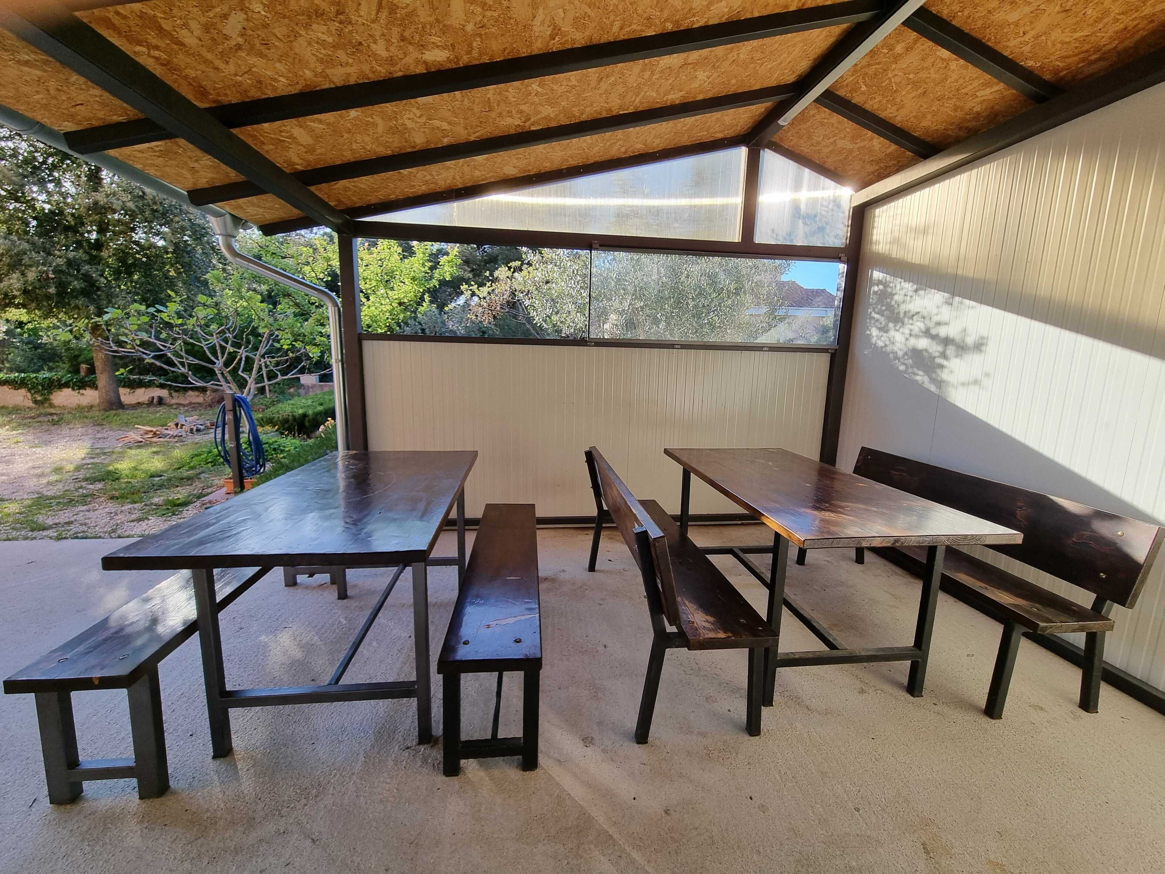 En udendørs terrasse med et overdækket siddeområde, inklusive borde og bænke.
