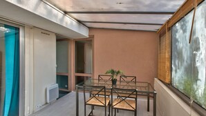 A small patio area with a glass table and chairs, a potted plant, and a view through a window. - Chic and spacious apart amazing terrace (Évry)