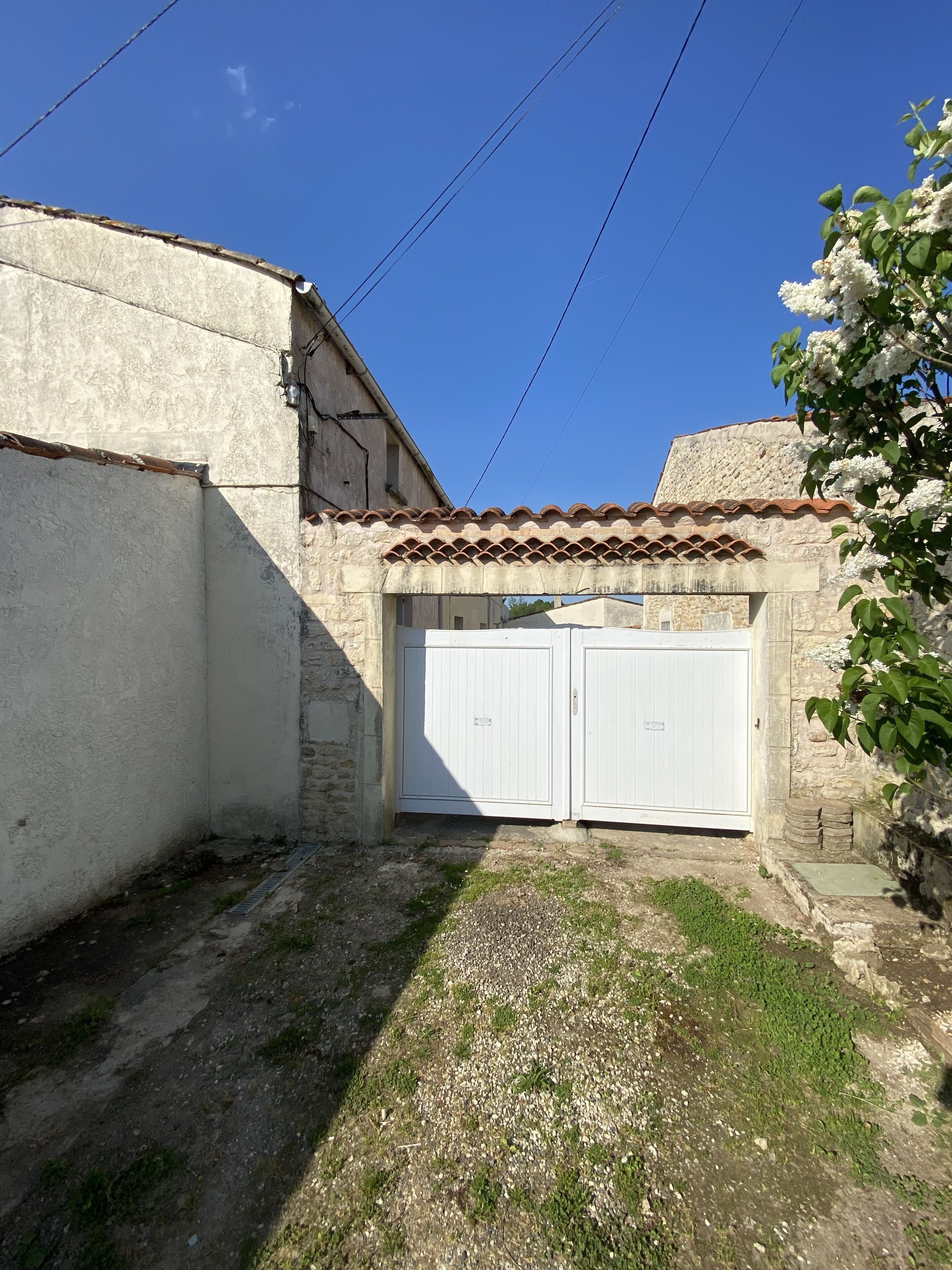 Un patio con un edificio blanco, techo de tejas y puerta de garaje blanca.