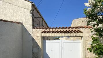 Un patio con un edificio blanco, techo de tejas y puerta de garaje blanca.