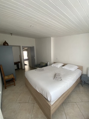 Une chambre à coucher avec un grand lit, une table de chevet en bois, une chaise et un bureau.
