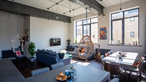 A modern living space with a sofa, hanging chairs, a dining table, and a TV. - Trafalgar Lane (Edinburgh)