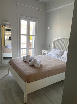 Relax in a serene space with a large bed, window, and mirror.