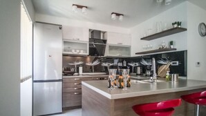 A modern kitchen with a central island, stainless steel appliances, and red bar stools.