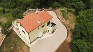 A two-story house with a red roof, a satellite dish, and a paved driveway.