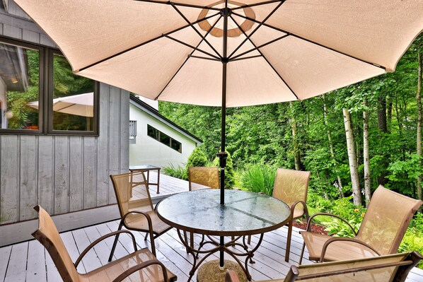 An outdoor patio with a round table and chairs, surrounded by a large umbrella.