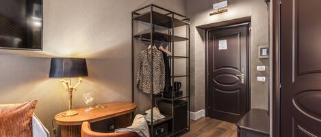 Habitación de hotel con cama, escritorio con lámpara, silla, armario y puerta.