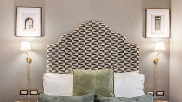 A hotel room with a geometric-patterned headboard, two bedside lamps, and framed pictures on the walls.