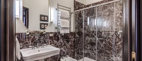 A bathroom with a marble sink, bidet, and a glass shower enclosure.