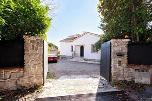 Un bâtiment blanc avec une entrée en pierre, une allée gravillonnée et une voiture garée.