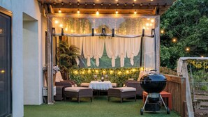 An outdoor patio with wicker furniture, a table with a white tablecloth, and a grill. - Taean Yoyo Kids Poolvilla (Taean)