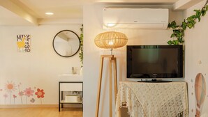 A living room with a flat-screen TV, a standing lamp, a mirror, and a wall-mounted air conditioner. - Taean Yoyo Kids Poolvilla (Taean)