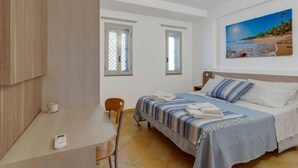Une chambre à coucher avec un lit, un bureau, une chaise et une fenêtre.