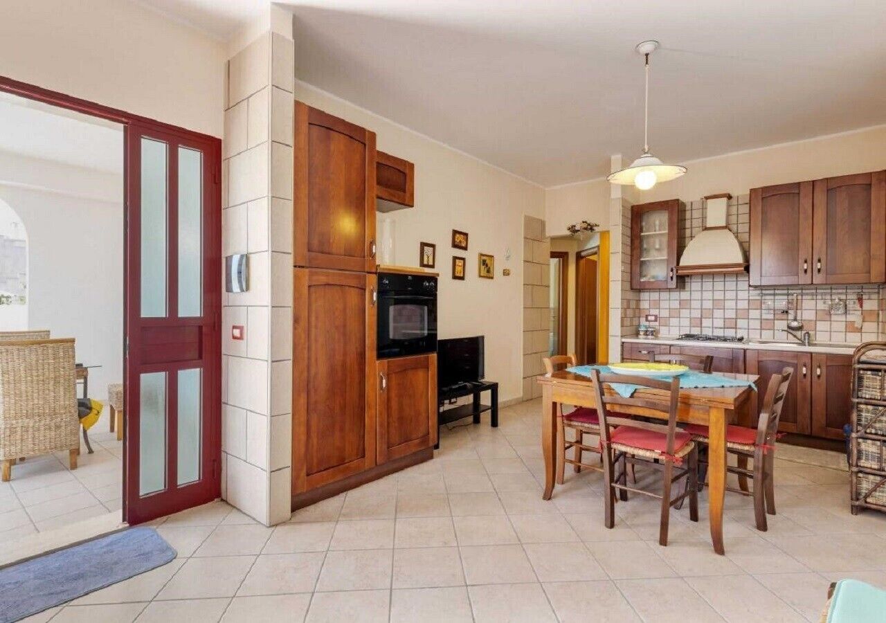 A compact kitchen with wooden cabinets, a dining table, and a TV.