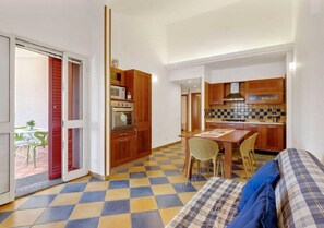 A compact room with a checkered floor, a bed, a dining table with chairs, a kitchenette, and a sliding glass door leading to an outdoor area. - Villa 'Rosimeli' close to the Beach with Pool & Wi-Fi (Ispica)