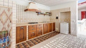 Une cuisine avec des meubles en bois, un pare-feu en carreaux et un sol à motifs.