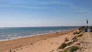 Une plage avec un ciel dégagé, un drapeau et quelques personnes.