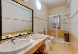Un baño con dos lavamanos, un inodoro y una zona de ducha.