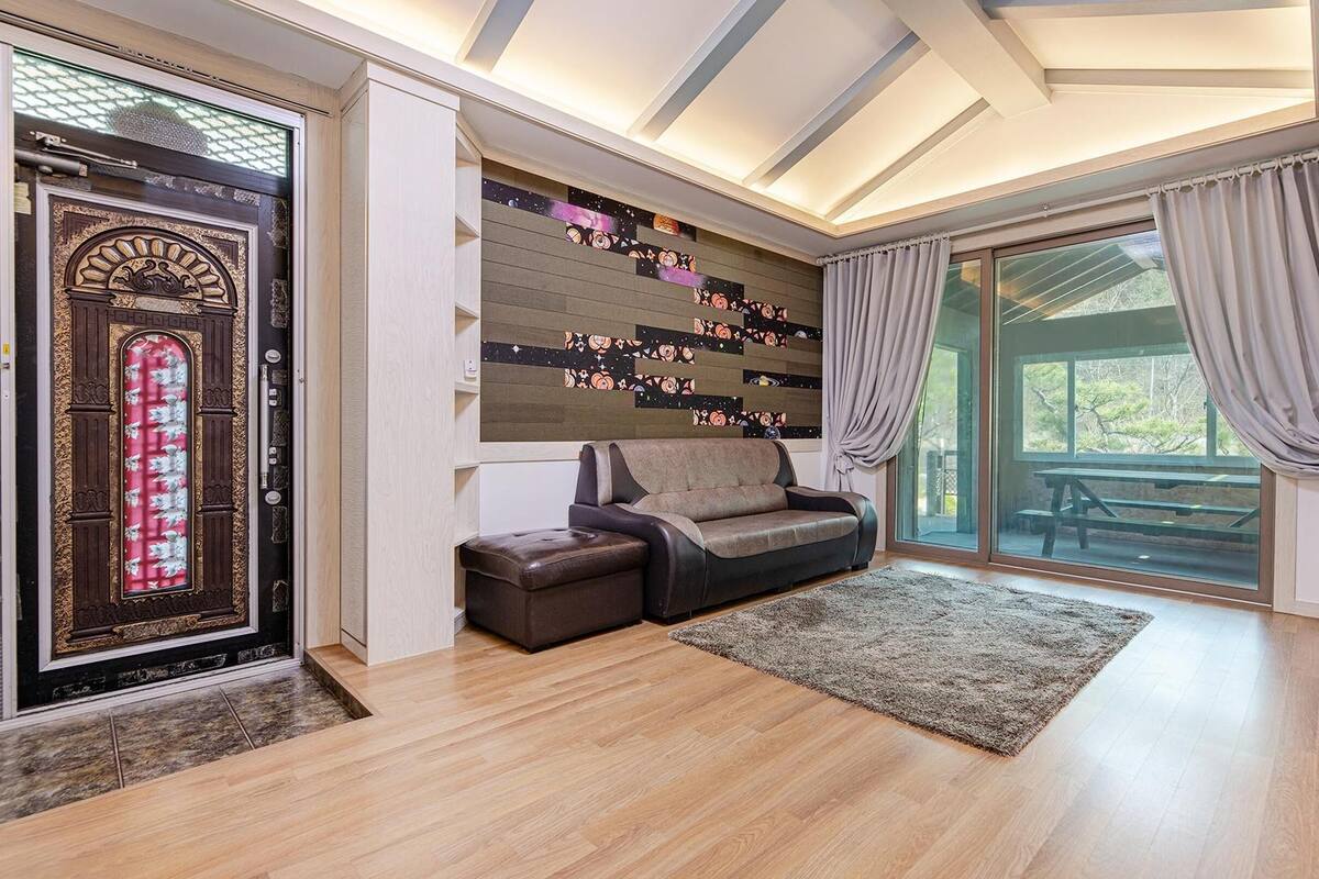 A modern living room with a sofa, ottoman, and a decorative wall with a space-themed design.