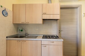 Una cucina con mobili in legno, un lavello in acciaio inossidabile e una stufa a gas.